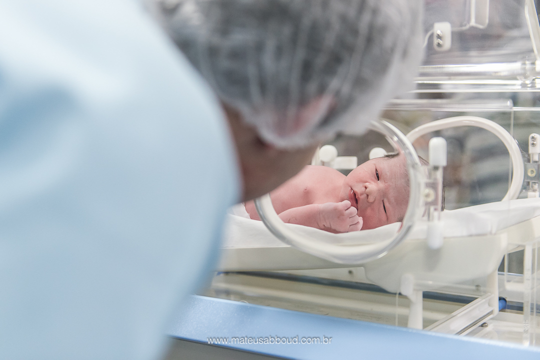 Pai olhando o bebê na encubadora no berçário.