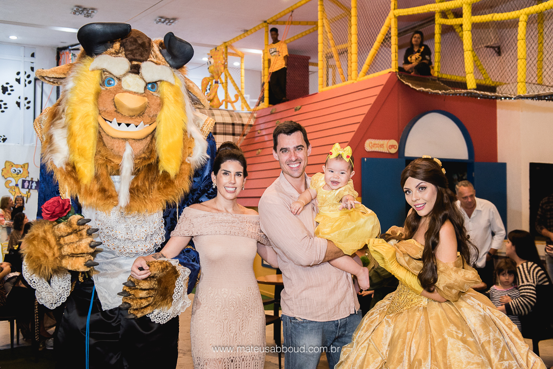 Personagens vivos de A Bela e A Fera, os pais e a niversariante posando para foto na festa de aniversário de 1 ano.