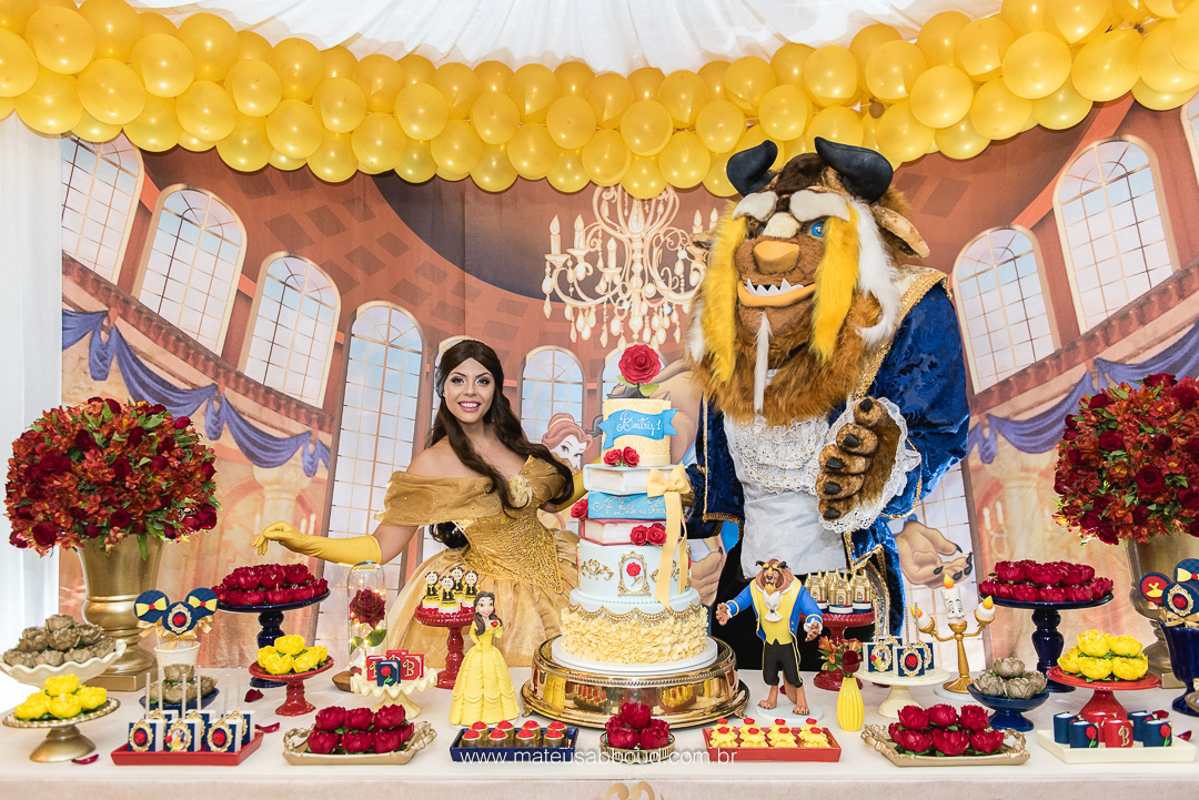 Personagens vivos de A Bela e a Fera atrás da mesa do bolo de aniversário de 1 ano.