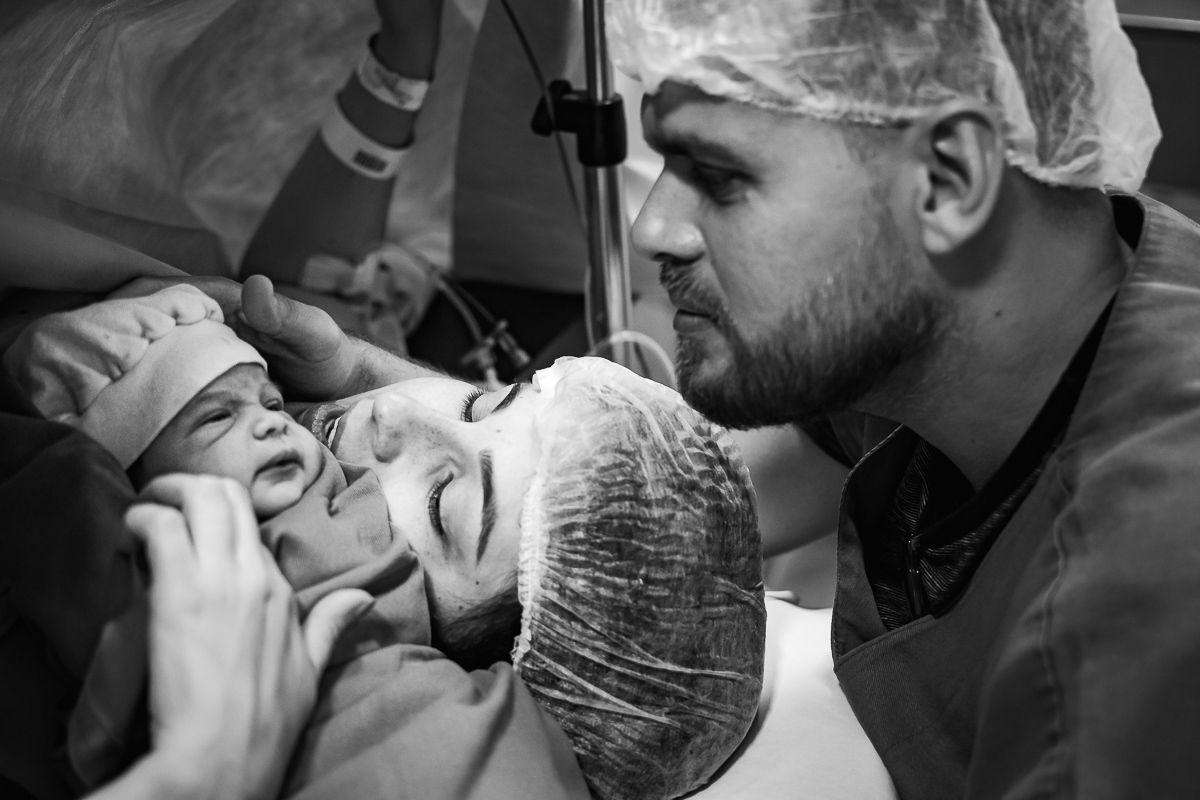 Foto mostrando toda a emoção e atenção dos pais com sua bebê que acabou de nascer