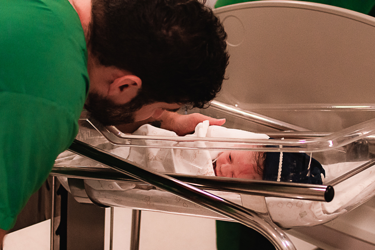 foto do pai admirando o bebê recém nascido no carrinho