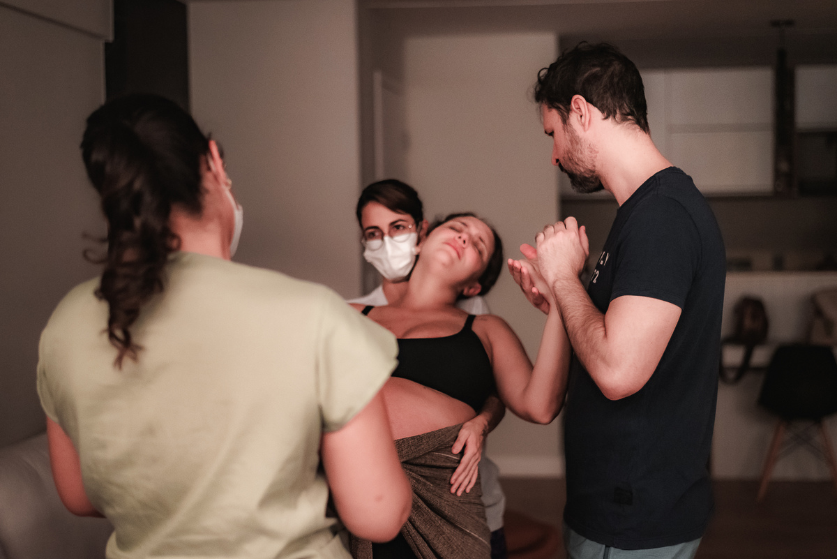 fotografia de parto pelo fotografo de parto andré pontes -doula e enfermeira obstétrica assistindo a mulher em trabalho de parto e pai dando apoio