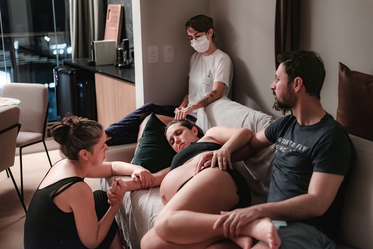 fotografia de parto pelo fotografo de parto andré pontes - doula, irmã e marido dando apoio à mulher em trabalho de parto