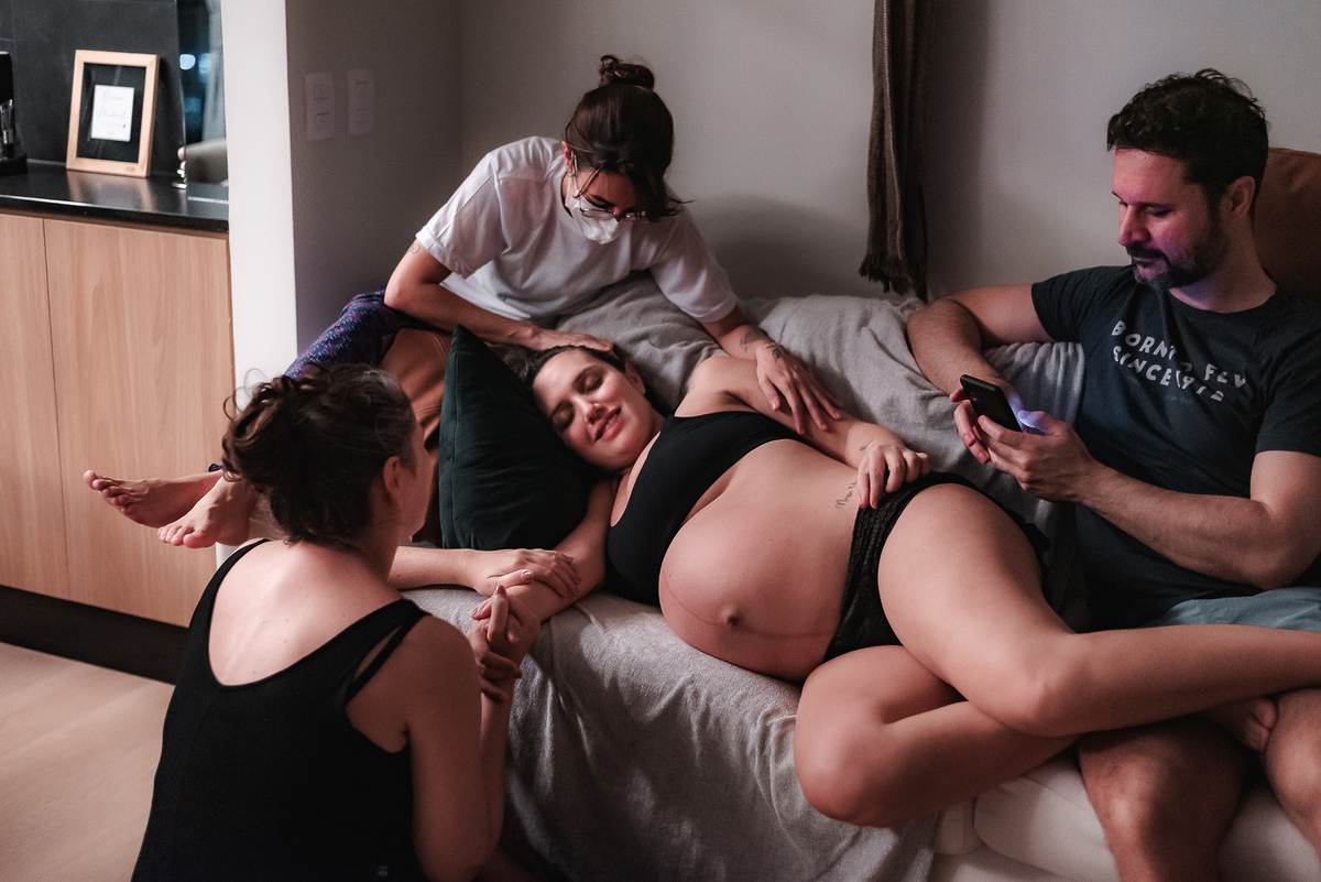 fotografia de parto pelo fotografo de parto andré pontes - doula, irmã e marido dando apoio à mulher em trabalho de parto