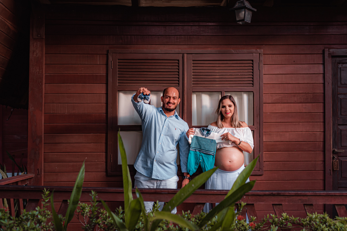 Papai com o sapatinho do bebê, mamãe com a roupinha do bebê, esperando o nascimento do primeiro filho.