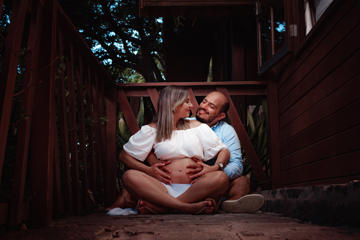 Linda foto do casal na varanda, aproveitando momentos de descanso antes do nascimento do primeiro filho.