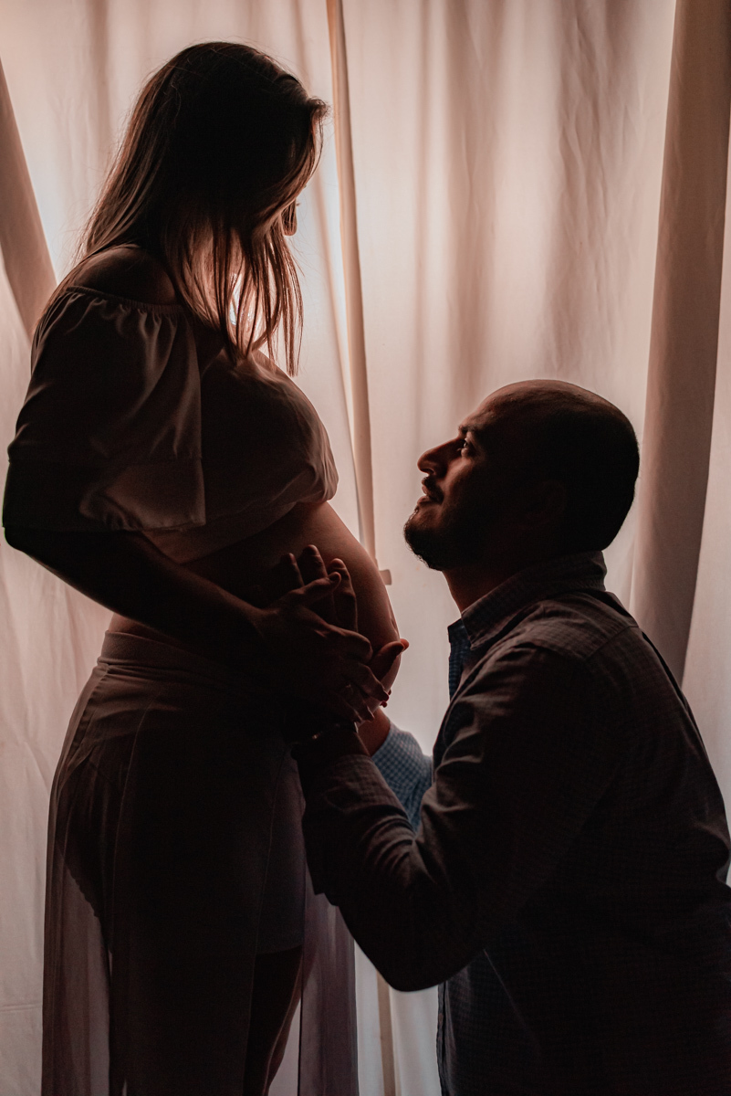 Papai admira a mamãe gestante, à espera do primeiro filho.