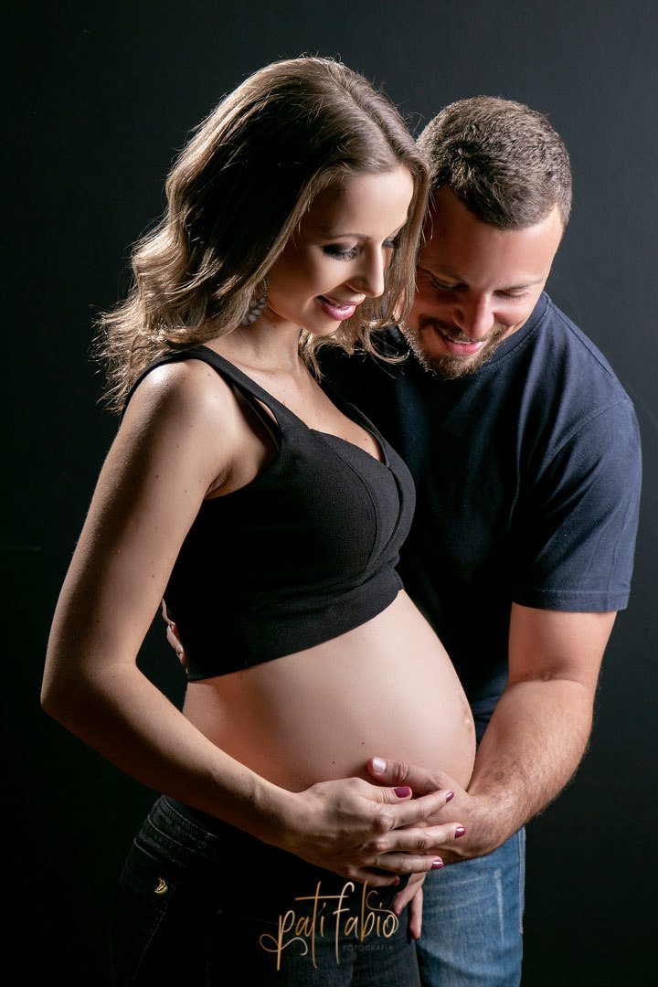 foto de gestante casal no estudio olhando a barriga