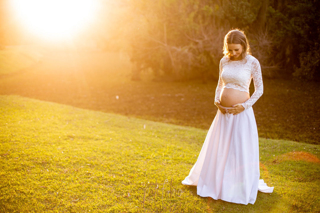 gestante no por do sol olhando a barriga