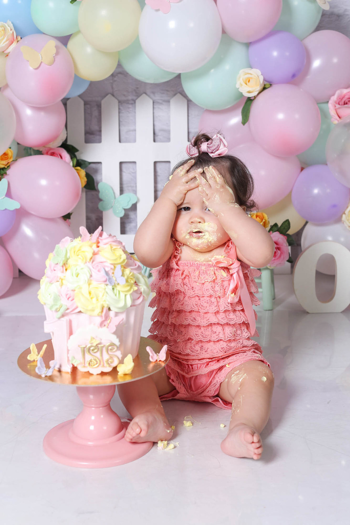 Foto com bolo de bebê se lambuzando e brincando em ensaio smash the cake