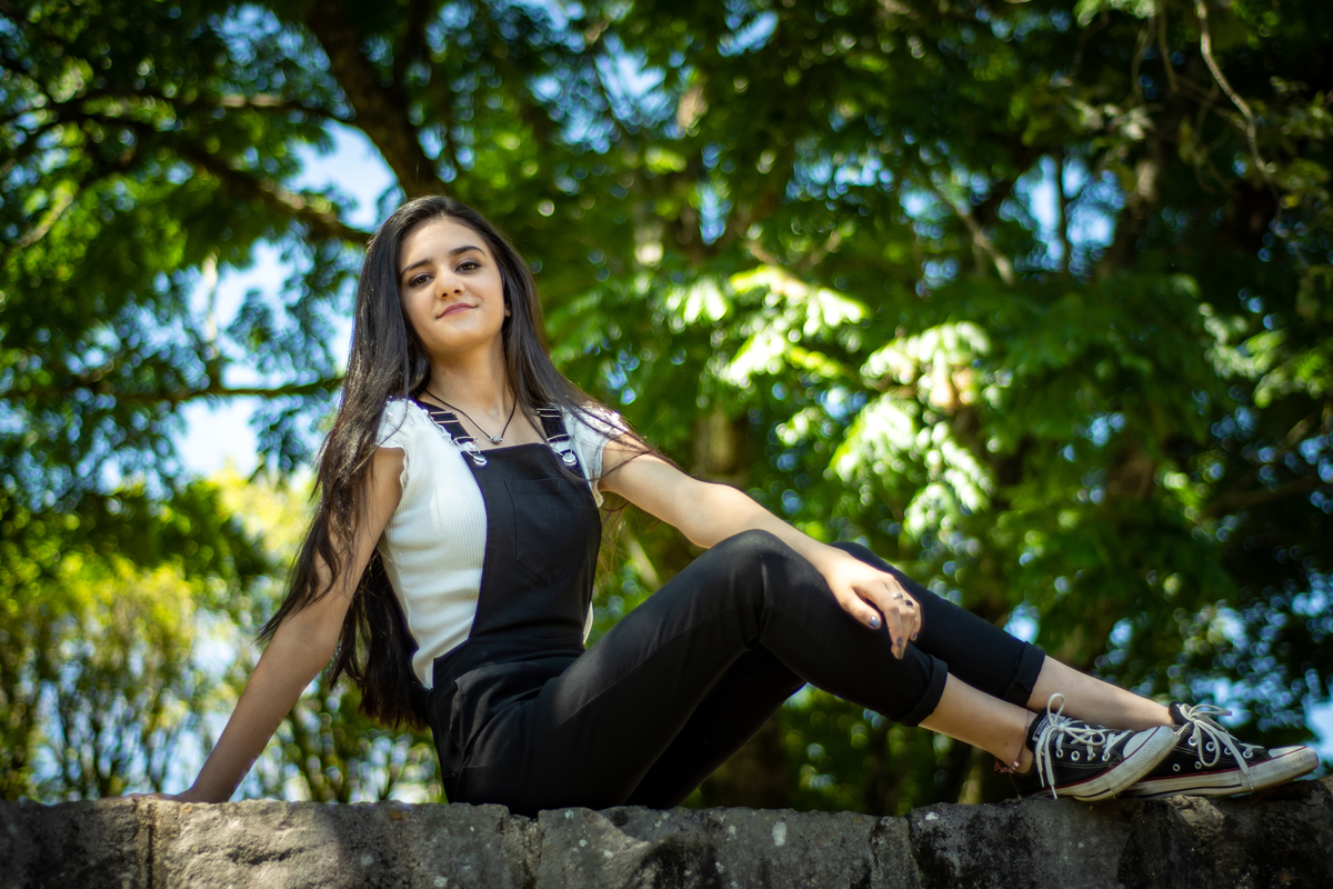 ensaio pessoal de 15th debutante luiza pelicioli em gramado nova petropolis canela rs fotografo de debutante em sao leopoldo casal boeira sentada sobre a pedra muro