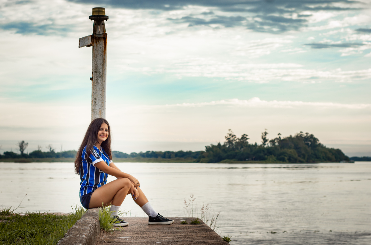 ensaio pessoal de 15th debutante kailany oliveira no cais maua em porto alegre rs fotografo de debutante em sao leopoldo casal boeira sentada ao lado do guaíba