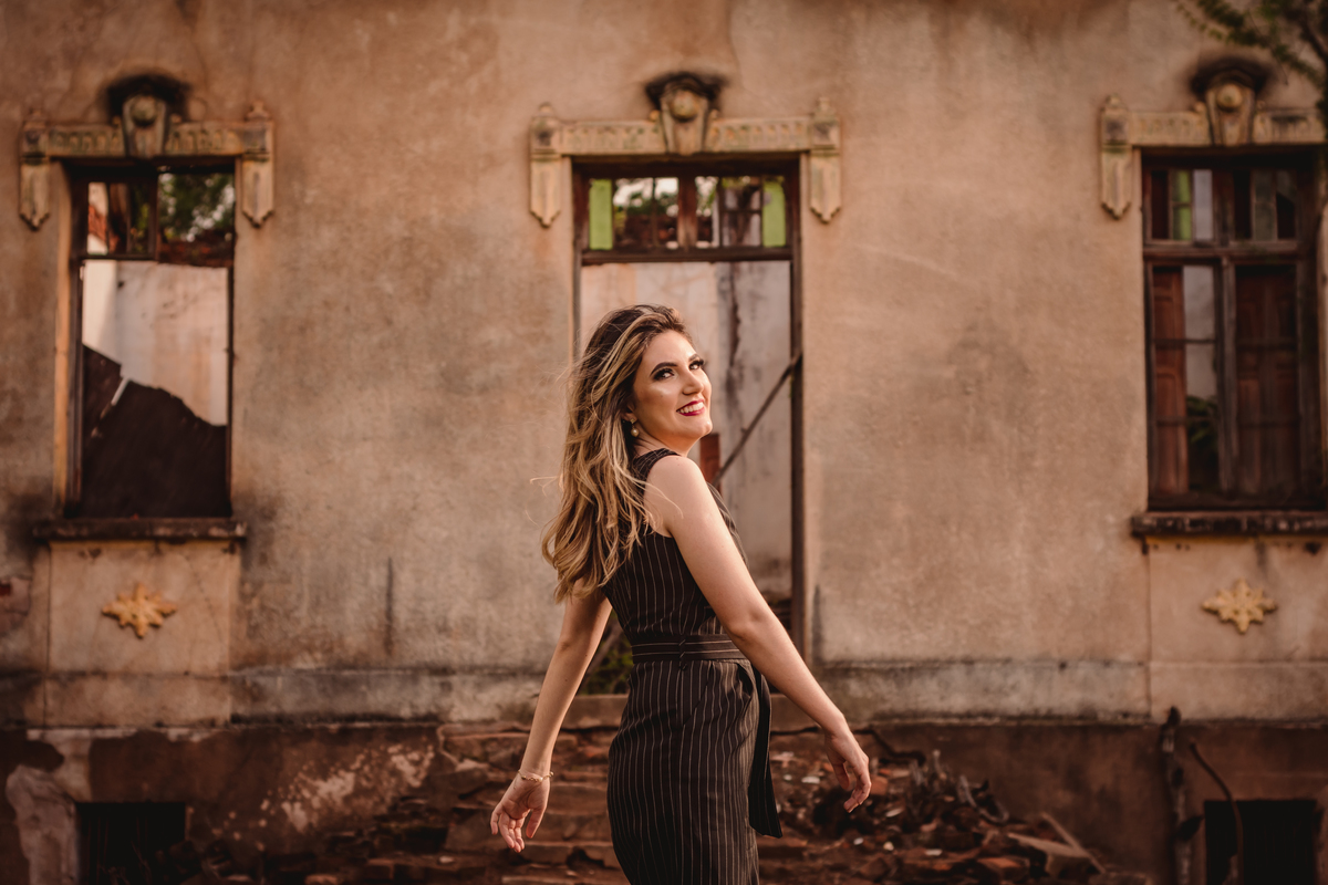 fotógrafo de formatura em são leopoldo fotografia de formando formanda pedagogia toga e capelo lilás ideias de fotos em ivoti são-leopoldo na rua dia nublado balanço das mãos e casa antiga