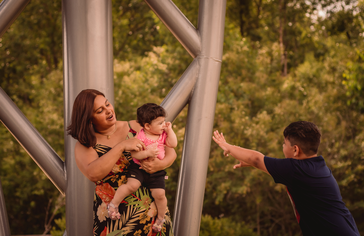 Book de Família em Canoas RS Fotógrafo de Família em São Leopoldo Fotos em família externo dia ensolarado dia nublado dia chuvoso capão do corvo parque getúlio vargas irmão brincando com irmã no colo da mãe