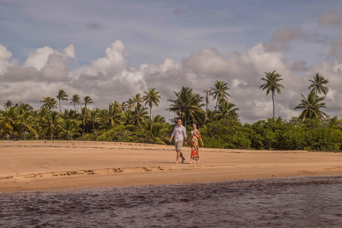Casal caminhando próximo à lagoa em Praia do Forte, aproveitando o cenário natural da Bahia.