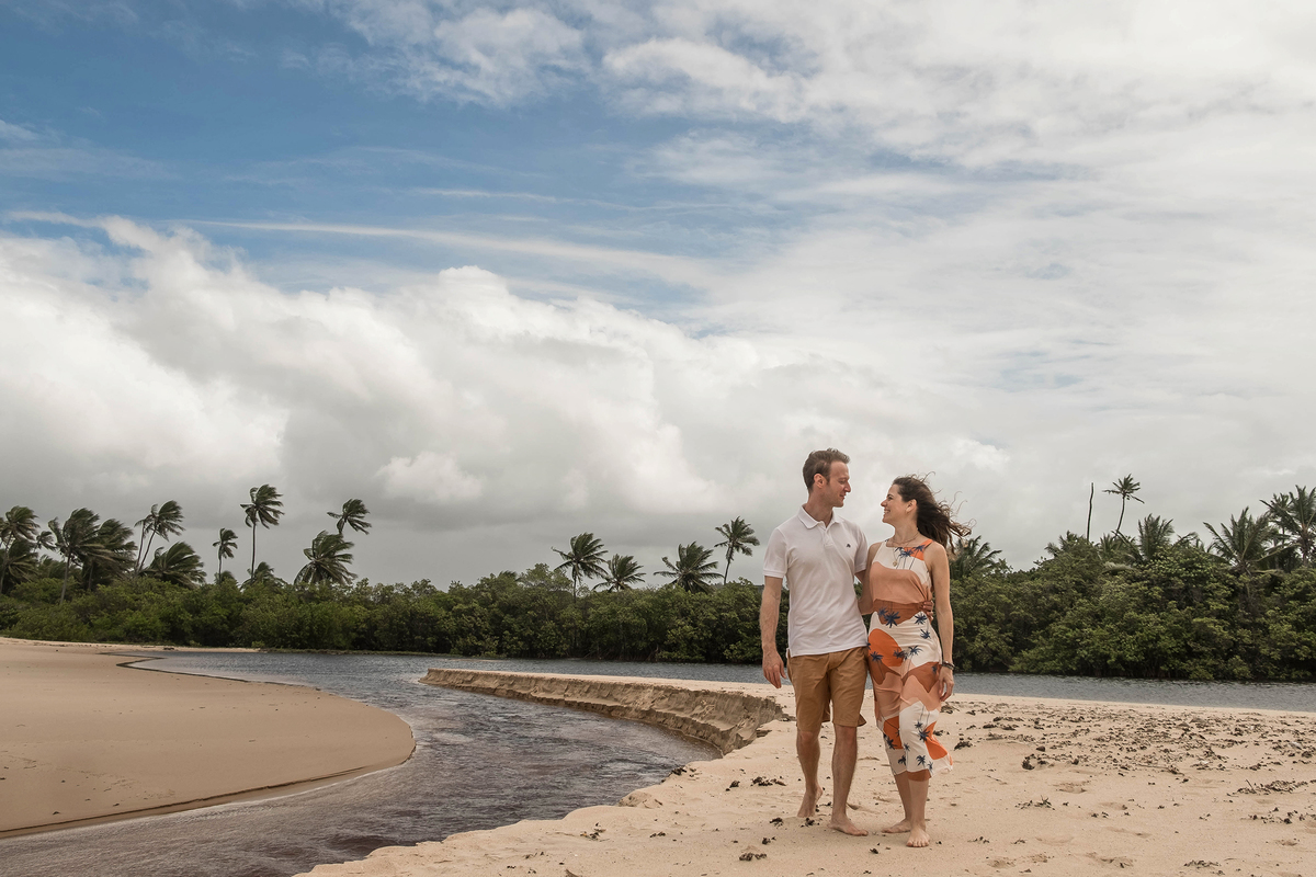 Mayara e denis caminhado na beira da lagoa Timeantube
 durante o ensaio de família na praia em Praia do Forte, Bahia.