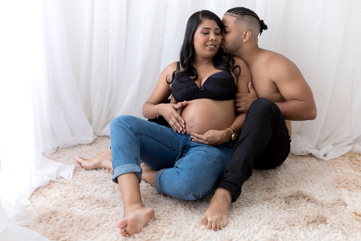 papai e mamãe sentados no chão e abraçando a barriga