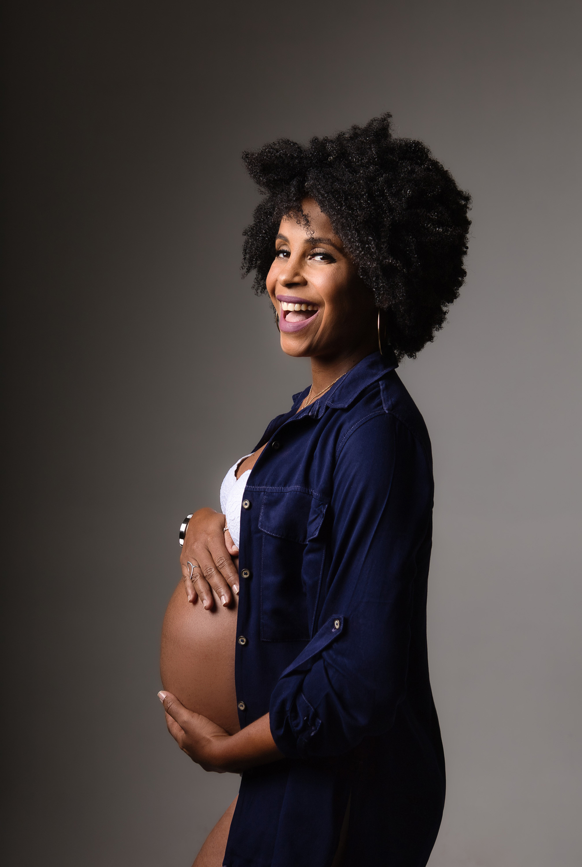 gestante sorridente com macacão e jaquetas jeans abraçando a barriga
