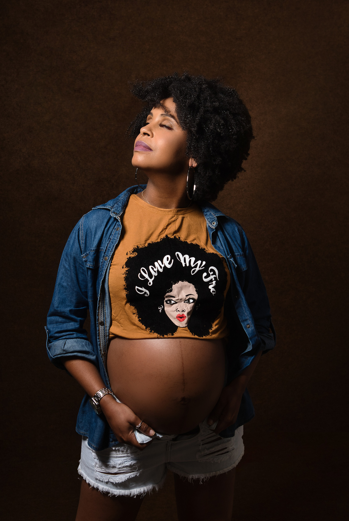 gestante com camisa e jaqueta jeans tocando na barriga