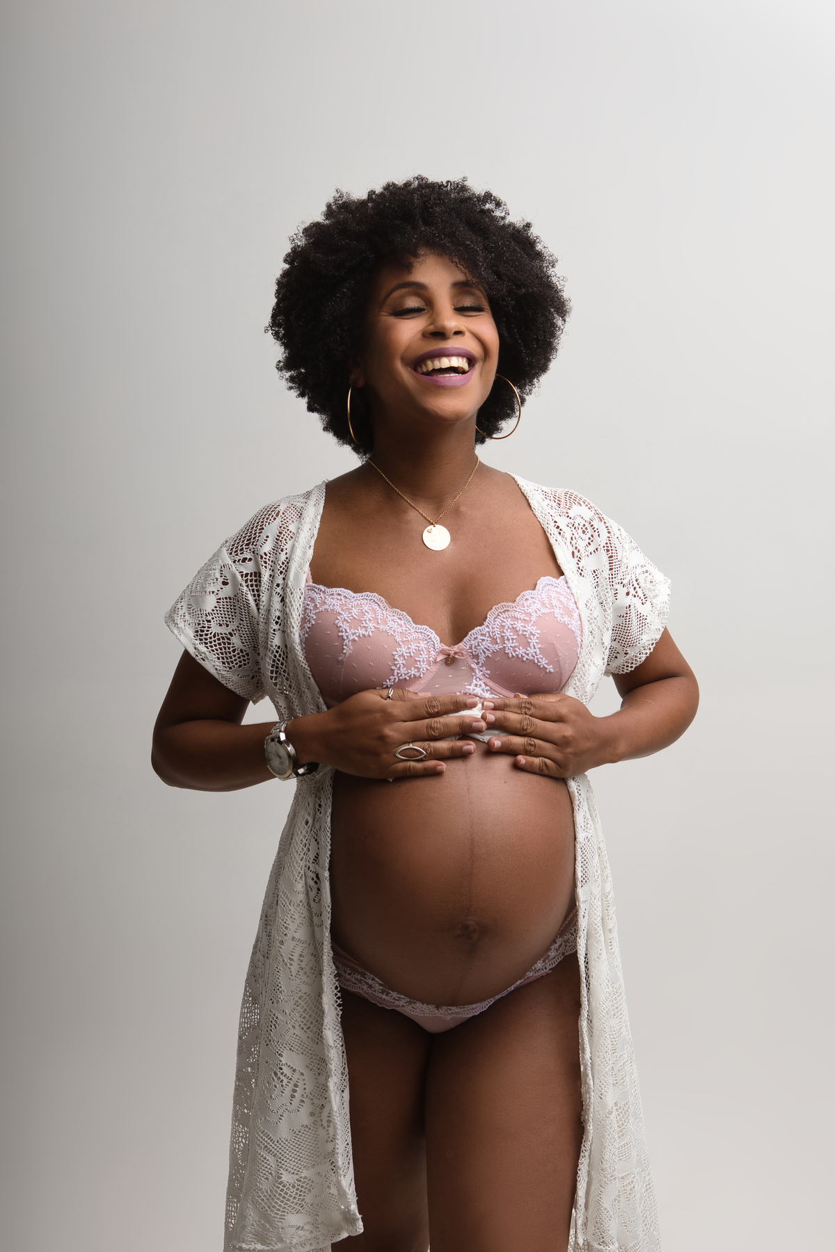 gestante boudoir sorridente com lingerie branca e tocando na barriga