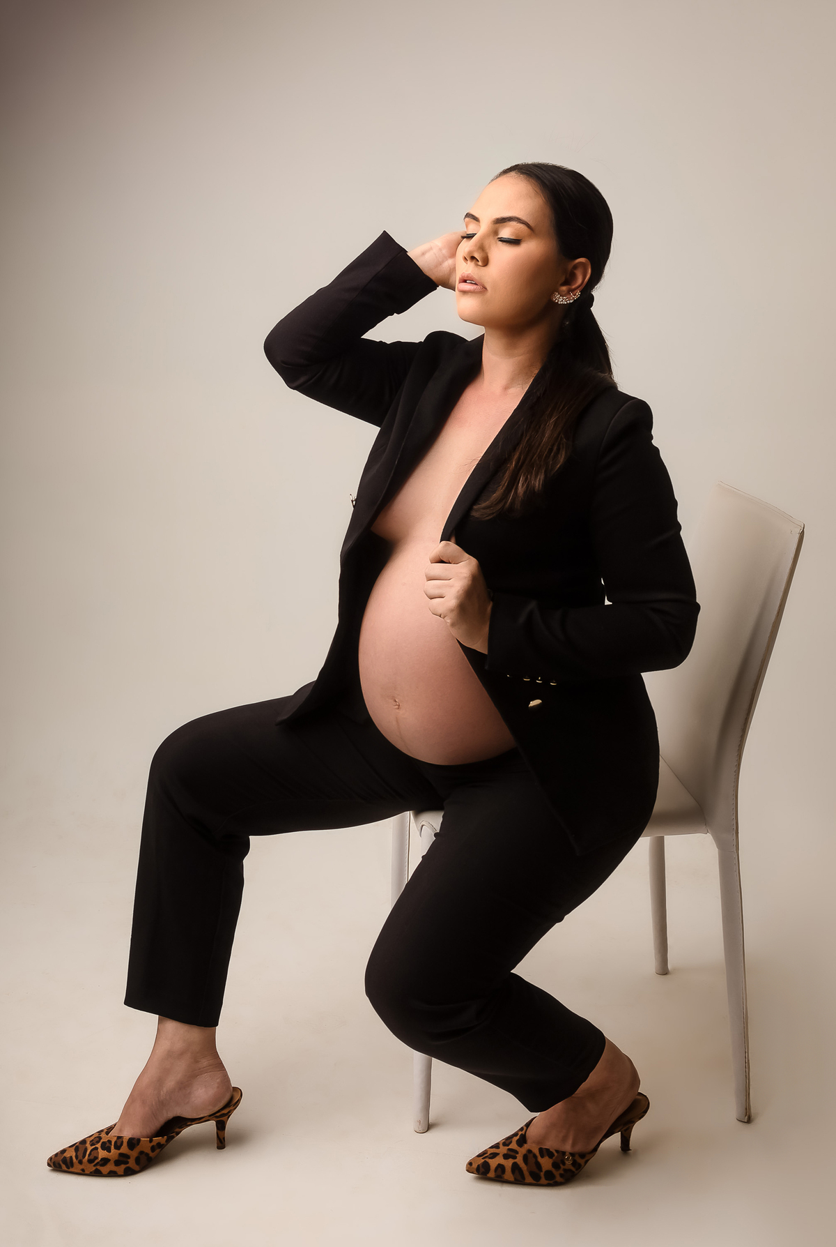 gestante sentada com calça e blazer preto