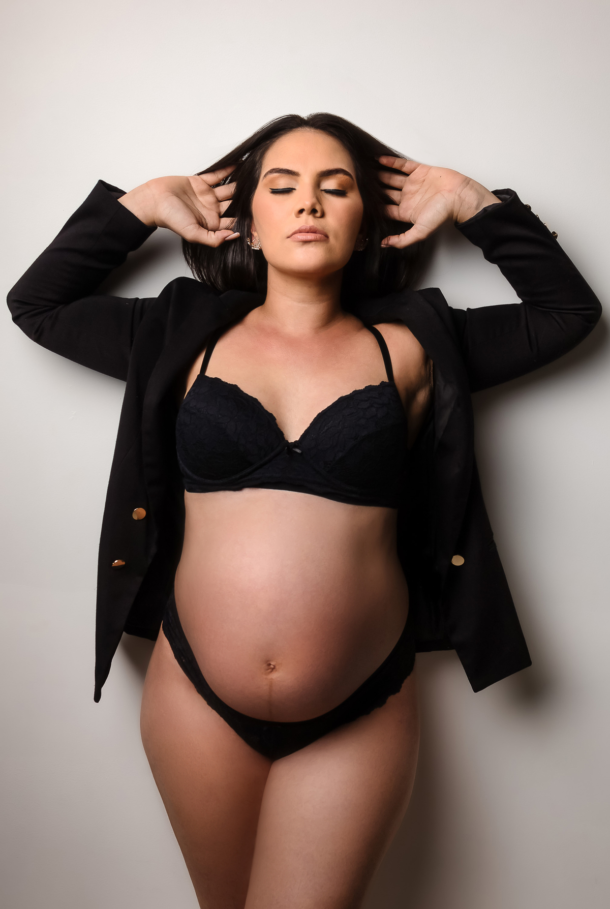 gestante boudoir com blazer preto e segurando o cabelo