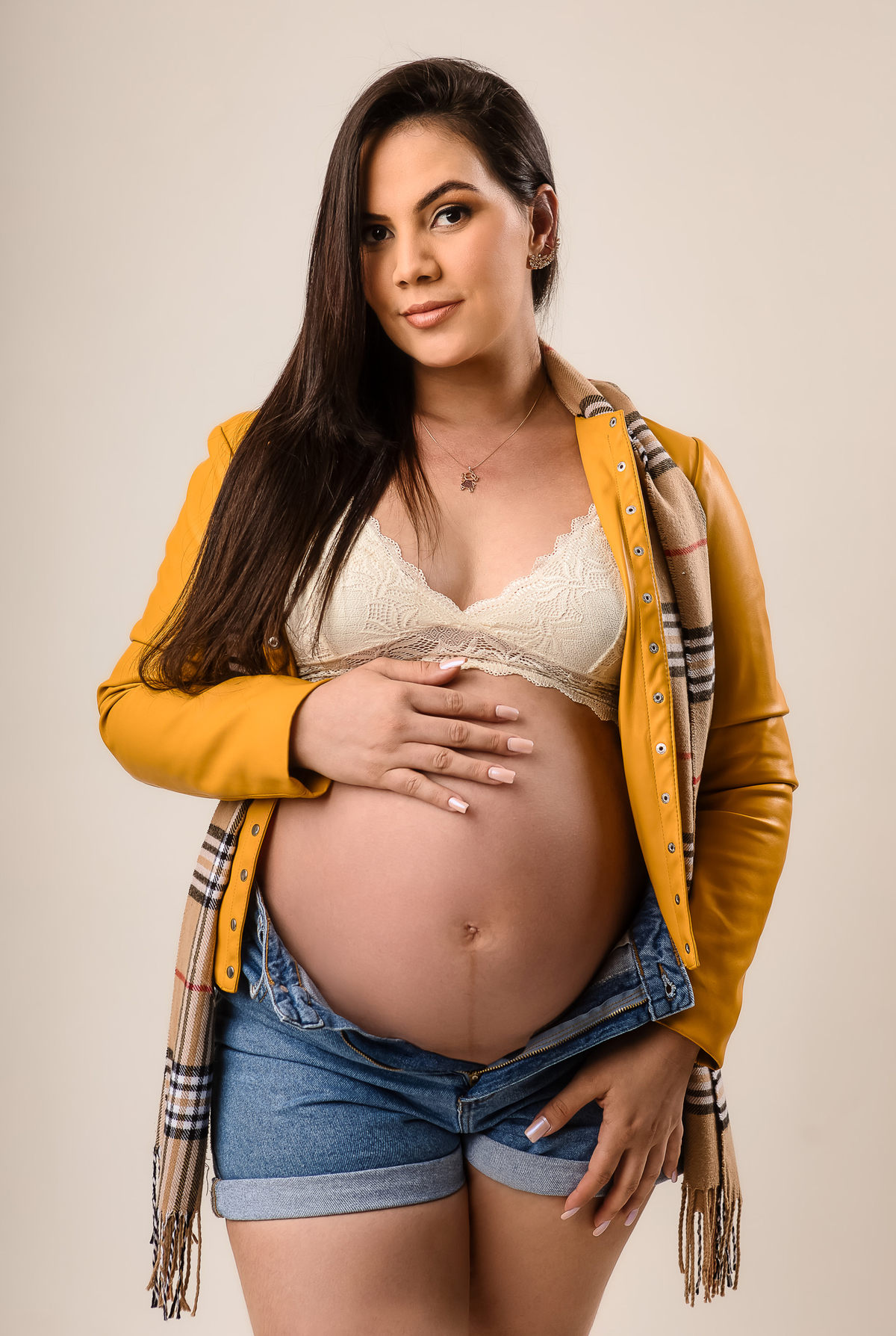 gestante com blazer amarelo e botas tocando na barriga