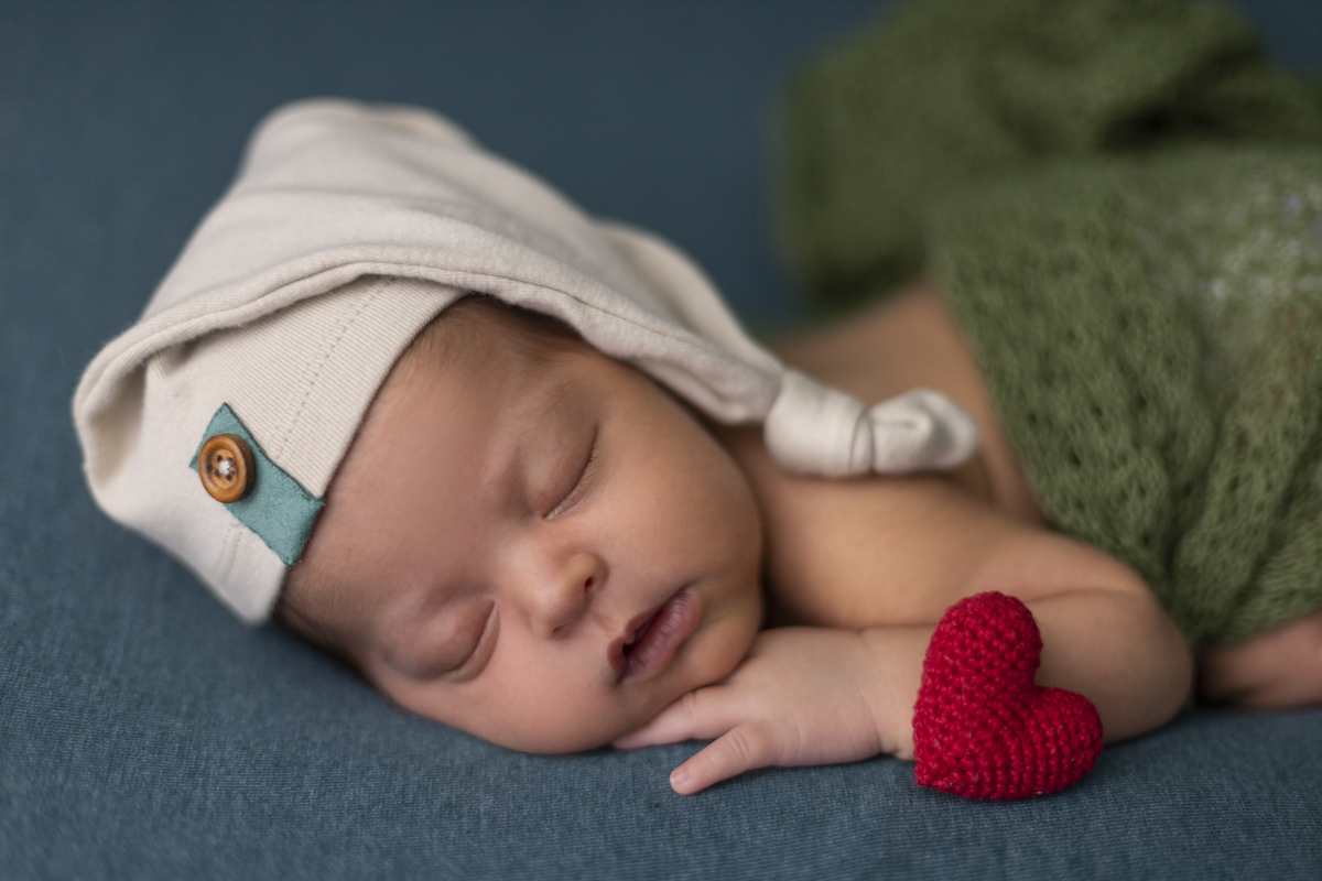 newborn de bruços com gorro e coraçãozinho