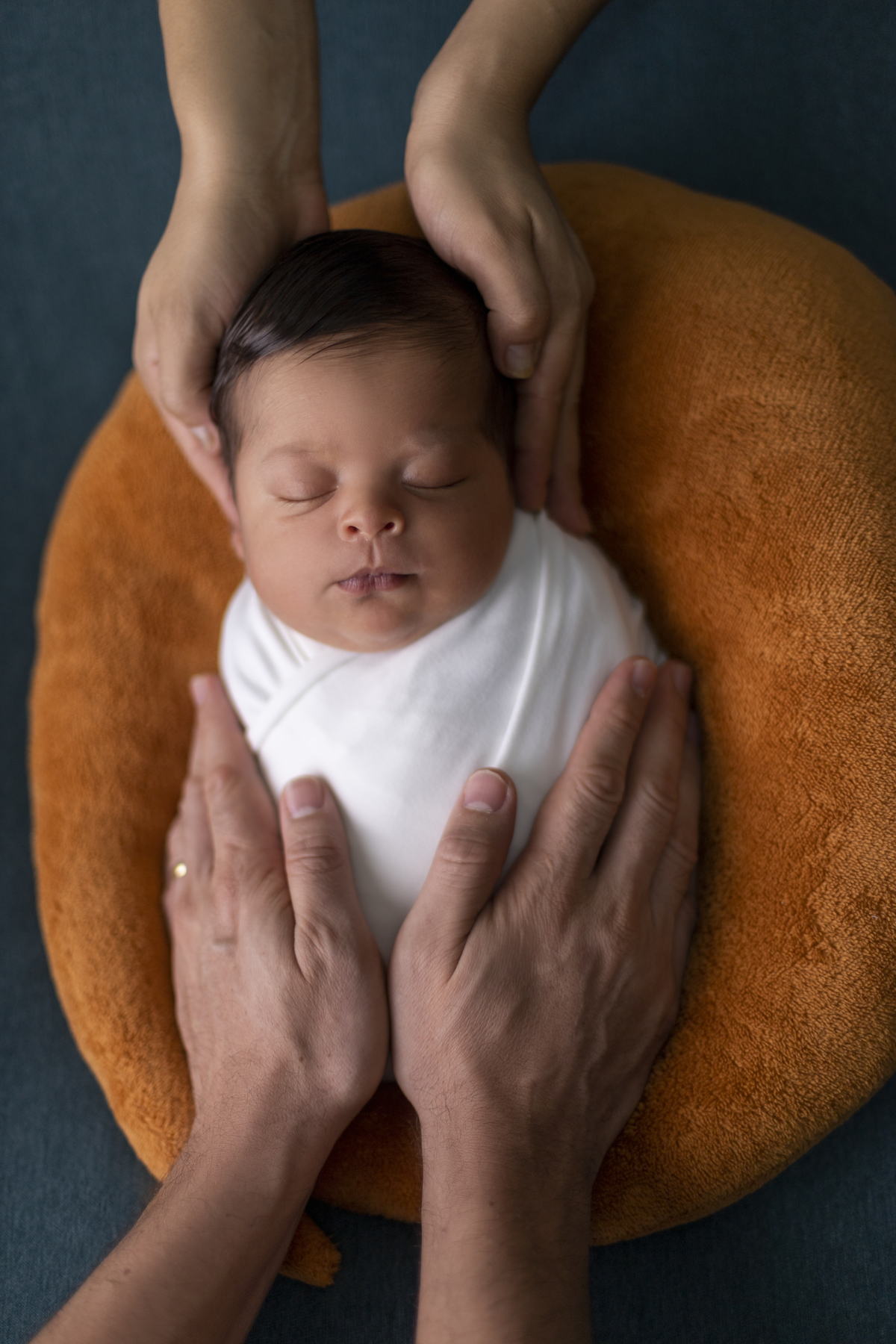 newborn coberto com as mãos de papai e mamãe