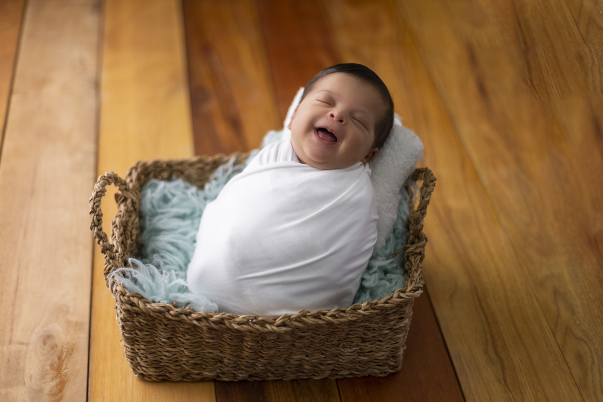 newborn sorridente coberto na cesta