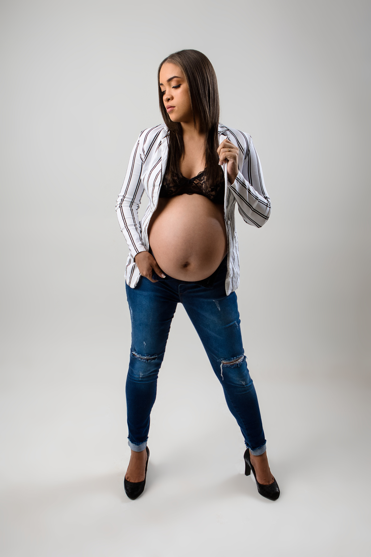 gestante segurando calça jeans e blazer segura