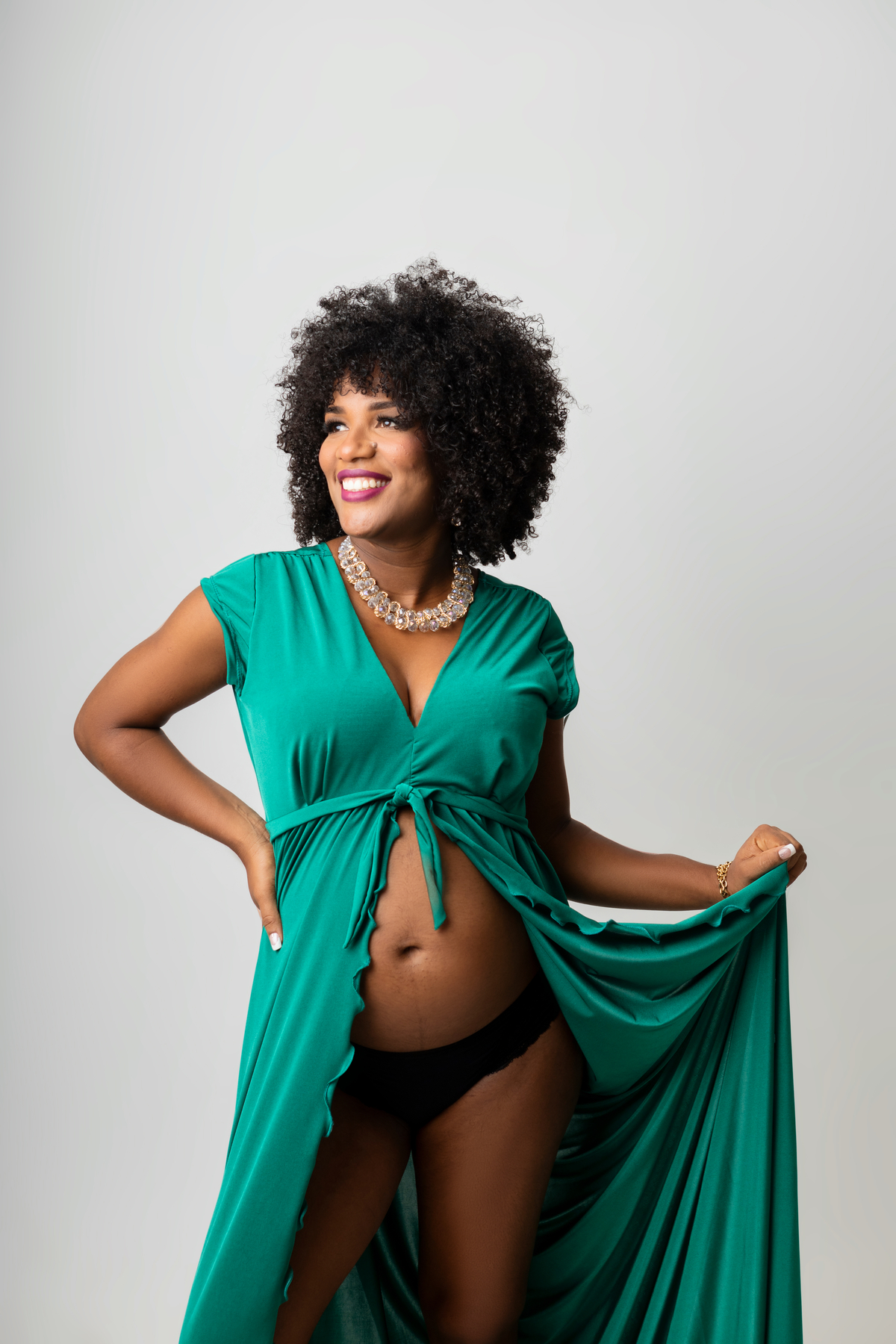 gestante de vestido com a mão na cintura e outra segurando o vestido