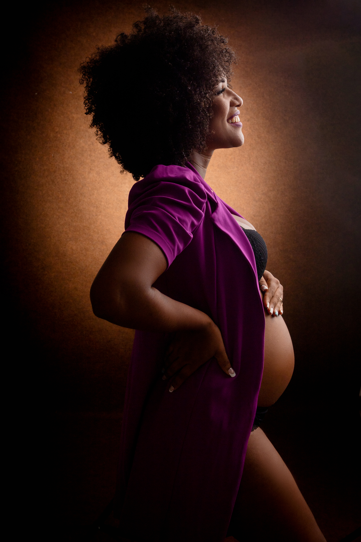 gestante boudoir com blazer com mão na cintura e outra na barriga