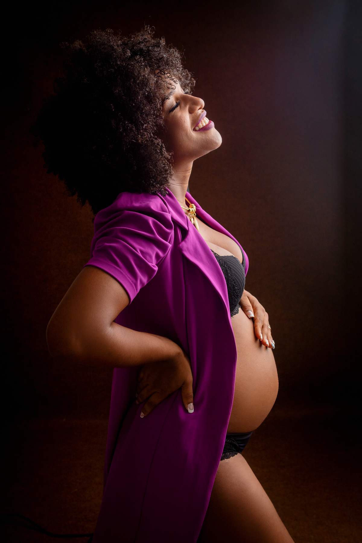 gestante boudoir com blazer com mão na cintura e outra na barriga