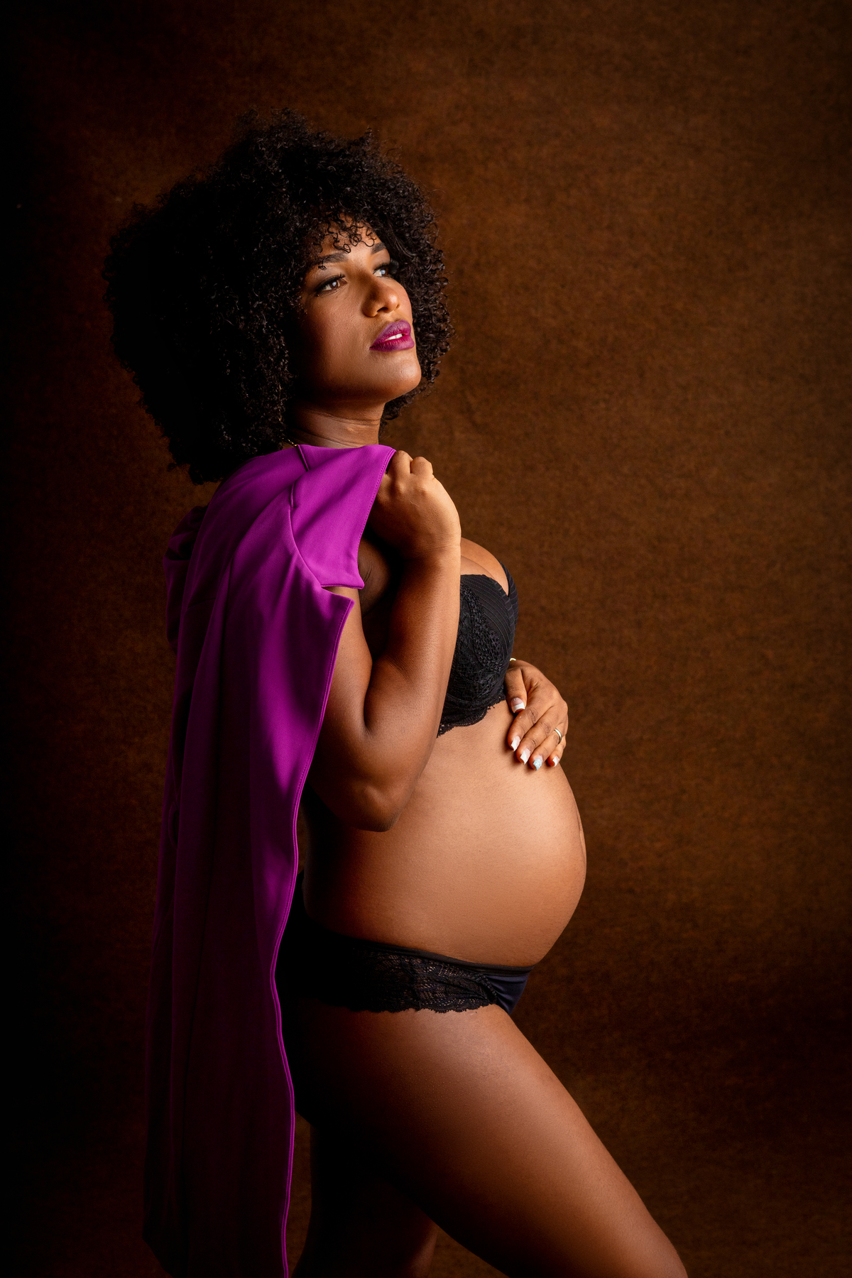 gestante boudoir segurando o blazer e tocando na barriga