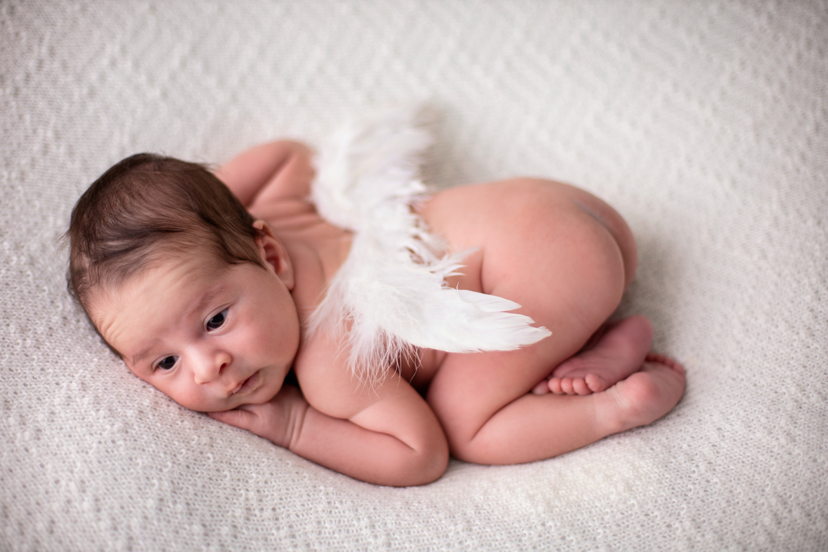 newborn de bruços com asas de anjo