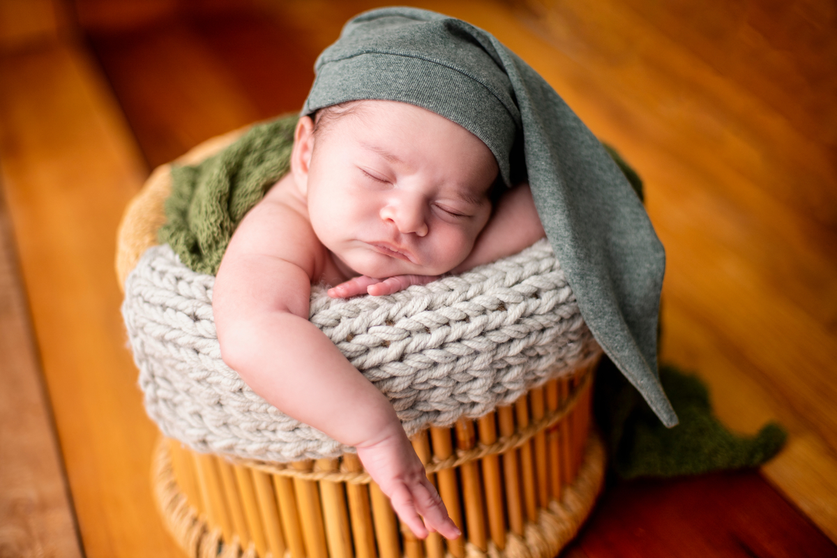 newborn coberto na cesta com gorro