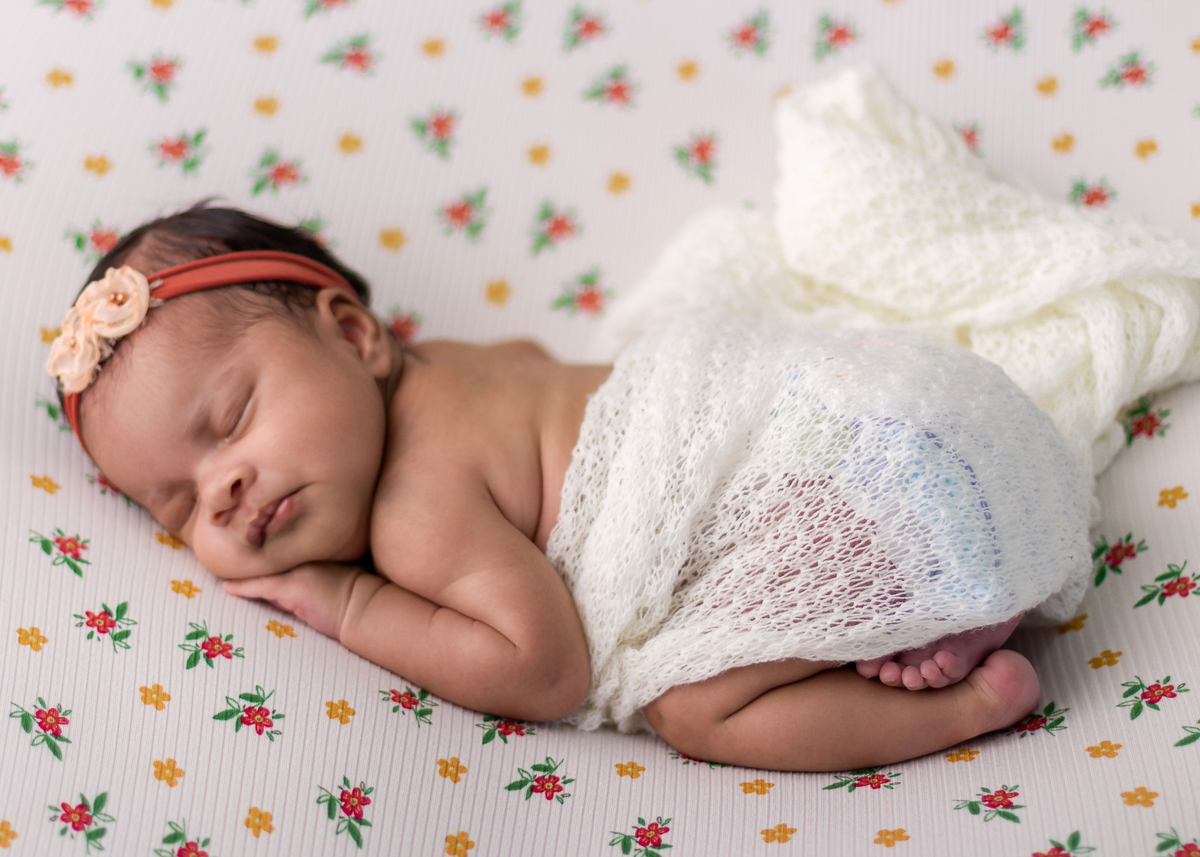 newborn de bruços com lençol e tiara