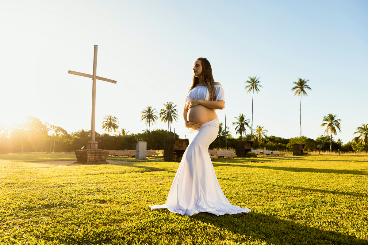 gestante abraçando a barriga com conjunto branco