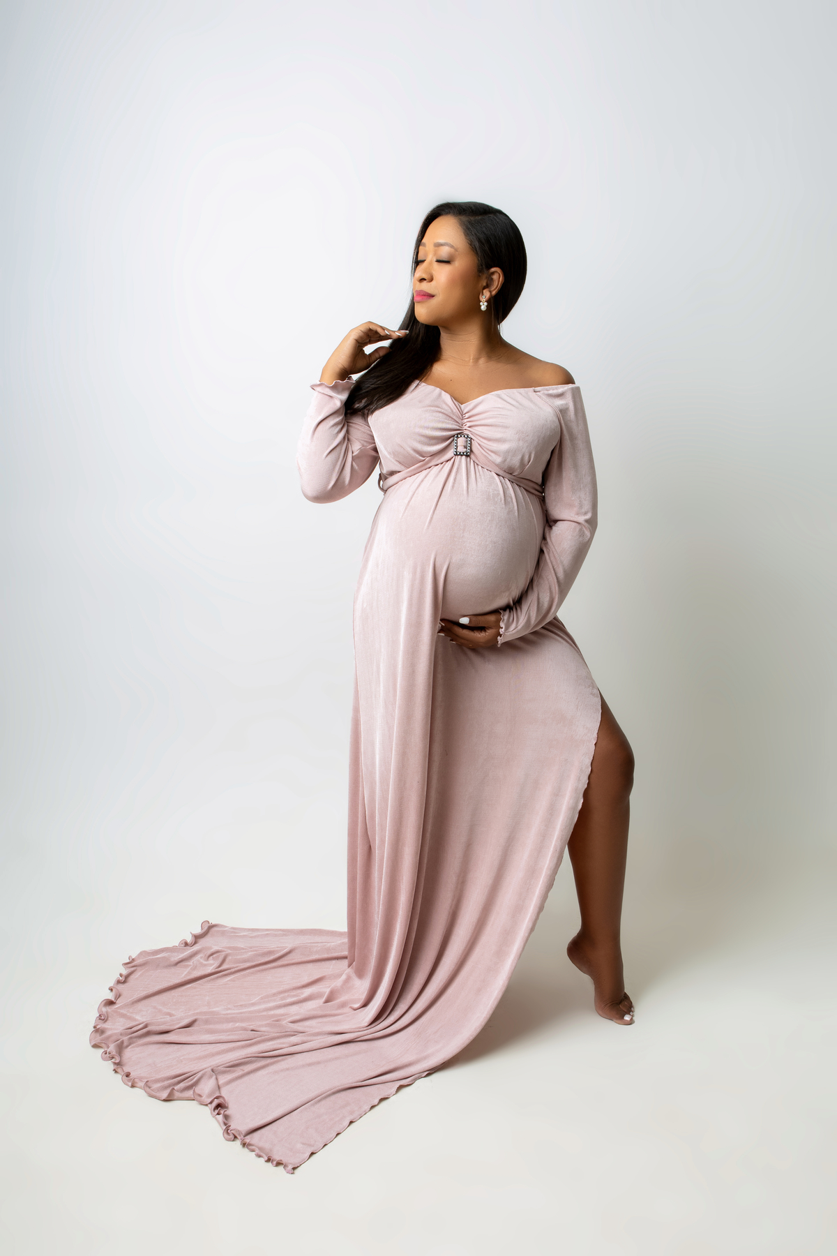 gestante de vestido longo segurando a barriga e o cabelo