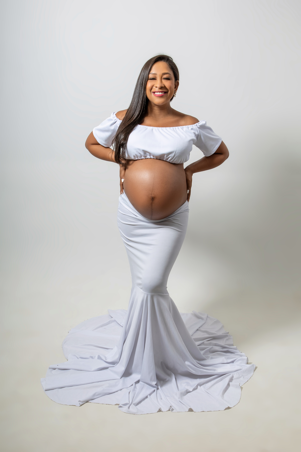 gestante de vestido longo com mãos na cintura