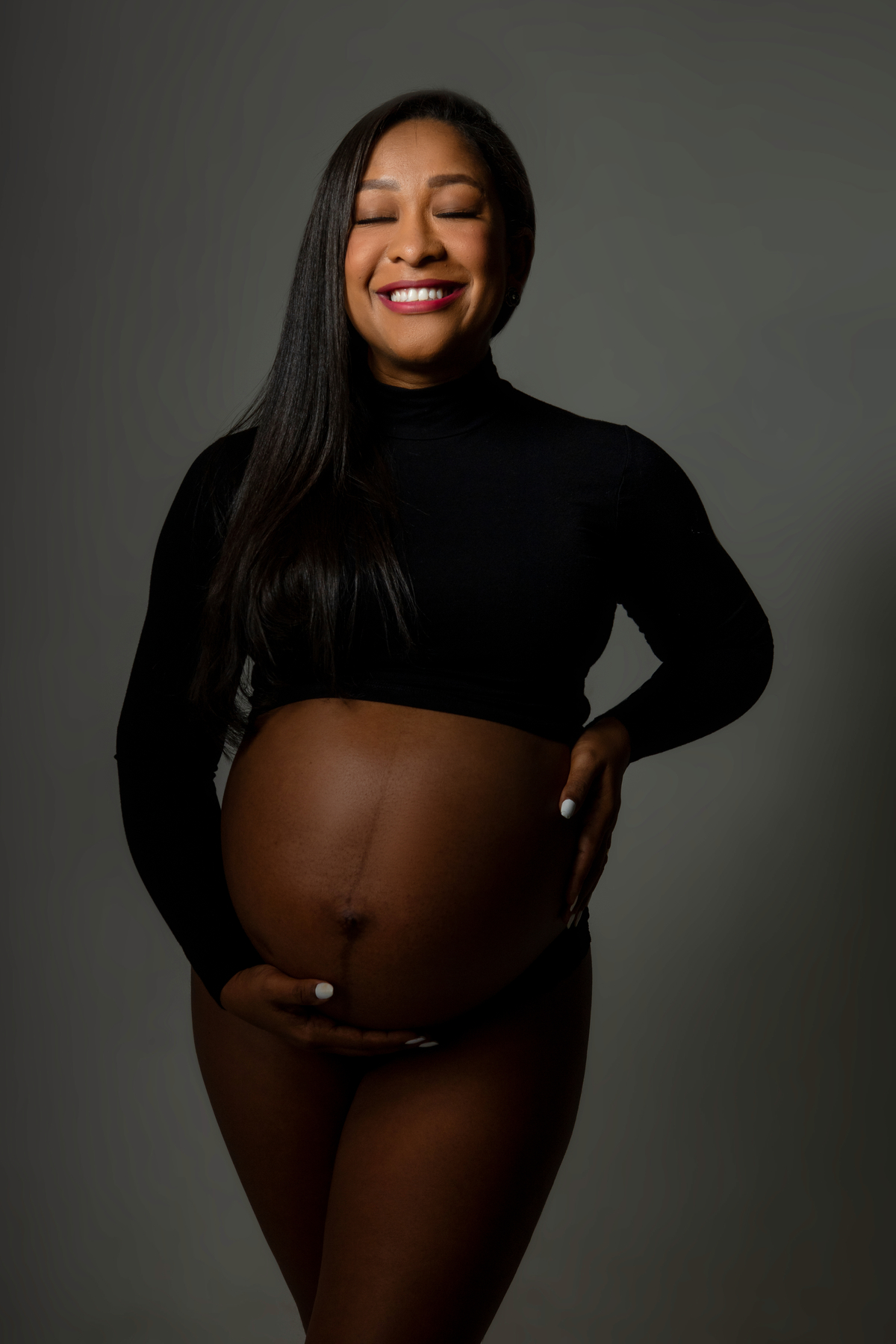 gestante de cropped manga cumprida com uma mão na barriga e outra na cintura