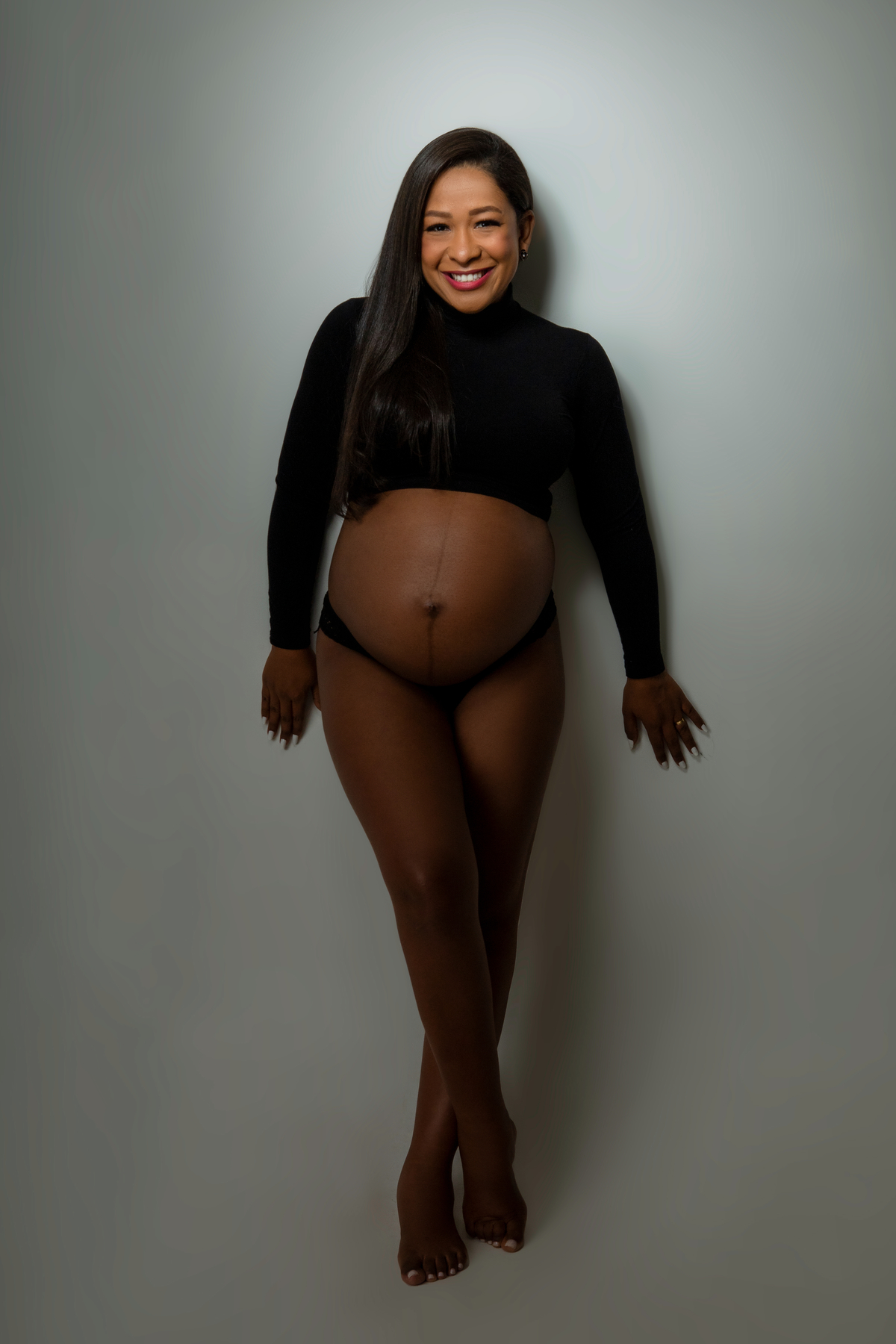 gestante de cropped manga cumprida encostada na parede