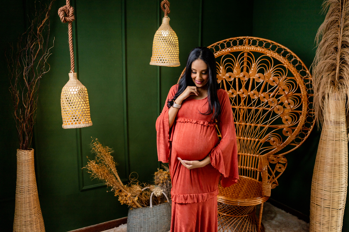 gestante olhando pra barriga e segurando o colar