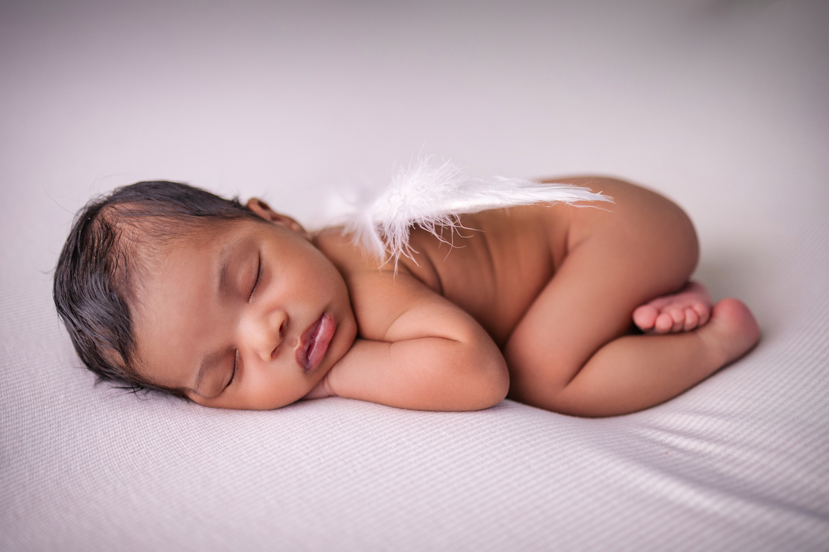 newborn de bruços com asas de anjo