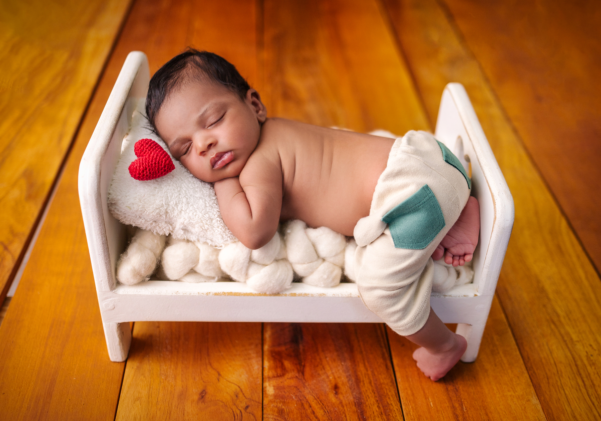 newborn de bruços na props cama com coração