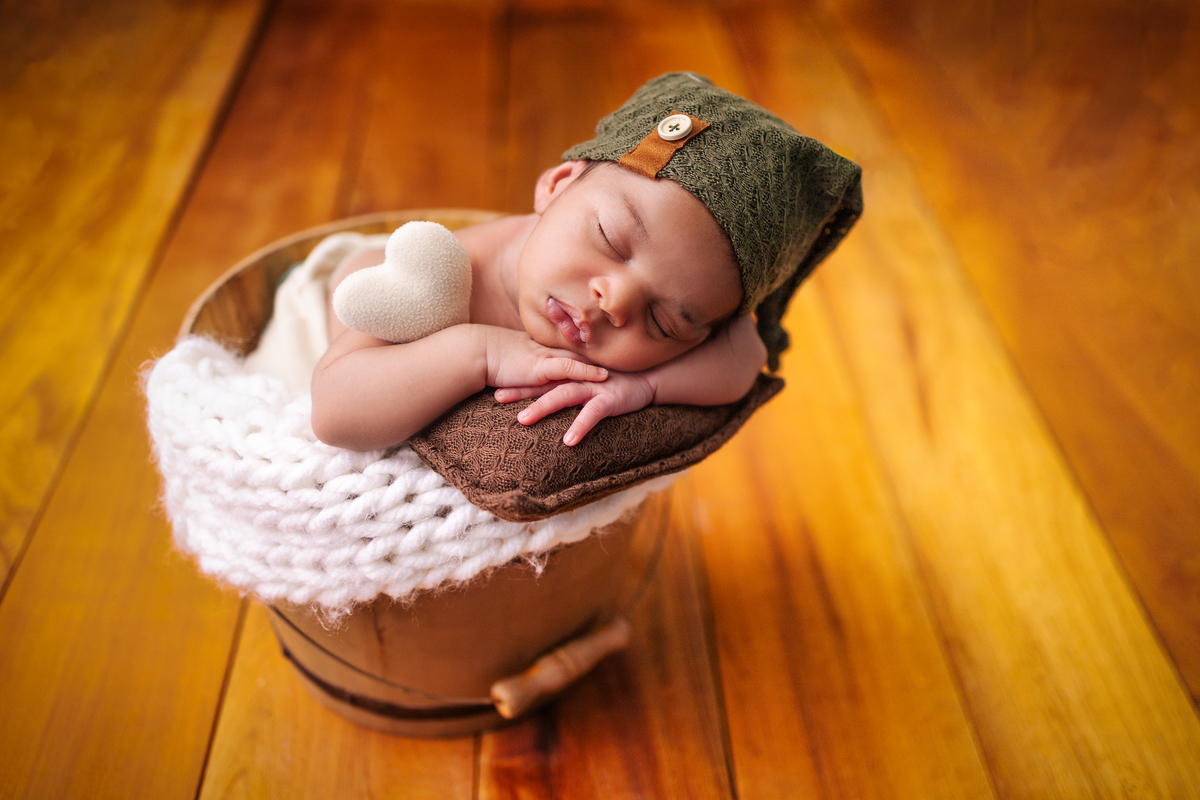 newborn coberto no balde com o gorro e coração