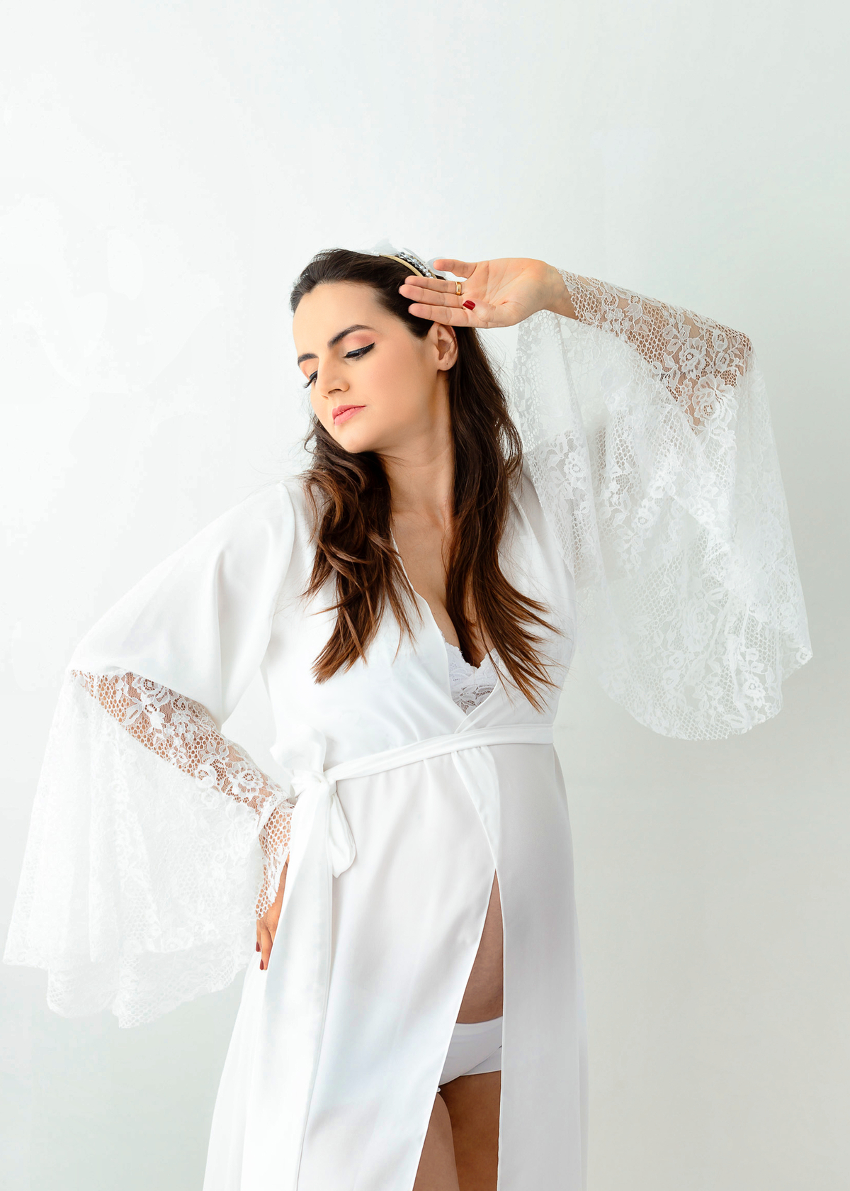 gestante boudoir com mão na cintura e outra na cabeça