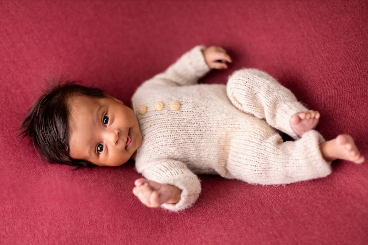 newborn de macaquinho deitado de barriga pra cima