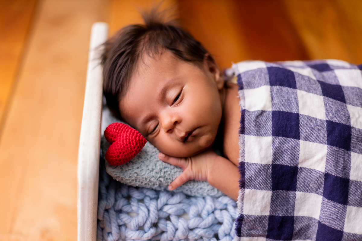 newborn de bruços na props cama e coração